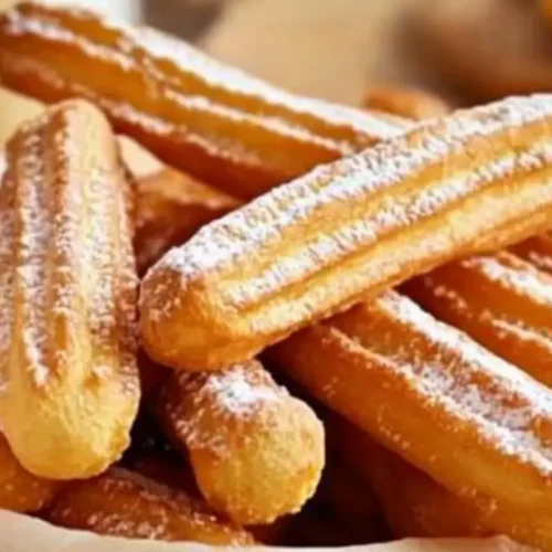 Churros maison dorés croustillants avec une fine couche de sucre glace, sur un fond minimaliste et lumineux